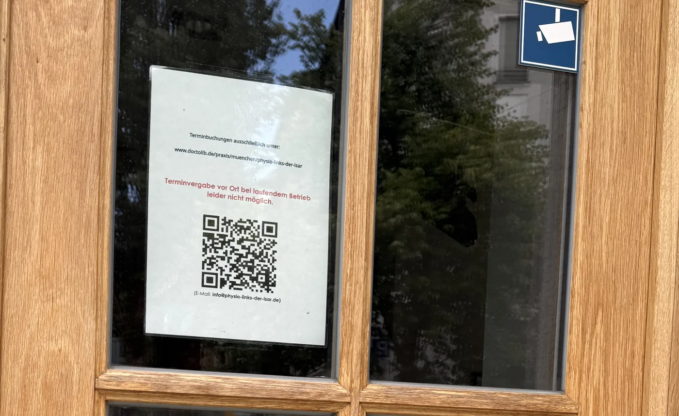 Hinweisschild an der Praxistür: Terminbuchungen ausschließlich online über Doctolib, mit QR-Code